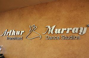 Arthur Murray Dance Studios features a sleek lobby with eye-catching logo signs.