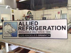 A lobby sign displaying the logo of Allie Refrigeration is prominently featured in the factory.
