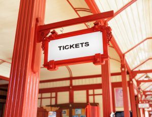 A red wayfinding sign hanging from the ceiling of a train station.