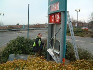 A man standing next to a gas station sign.