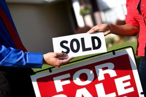 A person holding up a sign that says sold.