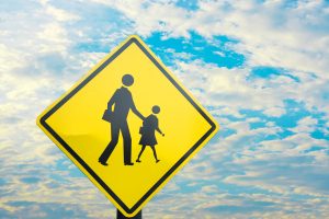 A yellow sign with an image of a man and child crossing.