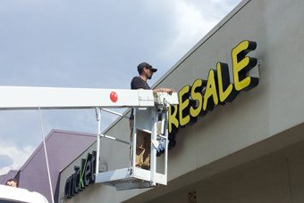 A man in a crane is working on the side of a building.