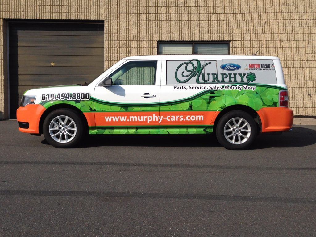 A white truck with an orange and green wrap.