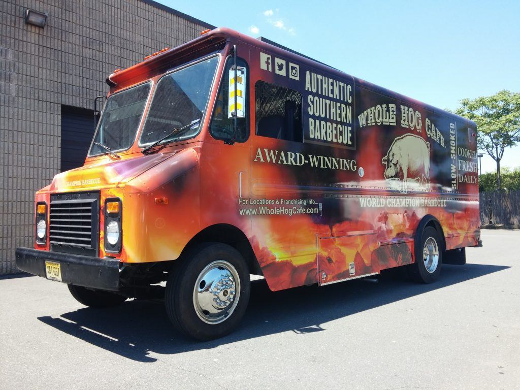 A food truck with an orange and red wrap.