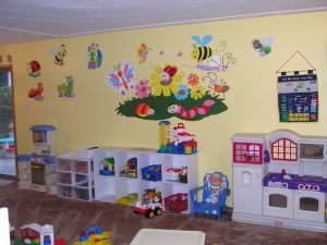 A yellow wall in a child's room with wall graphics for decoration.