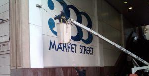 A man is cleaning a sign on the side of a building.