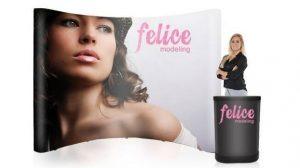 A woman is standing next to a black coffee cup and a pop up display.