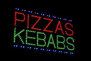 A neon sign that says pizzas kebabs.
