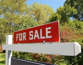 A for sale sign on top of a white fence.