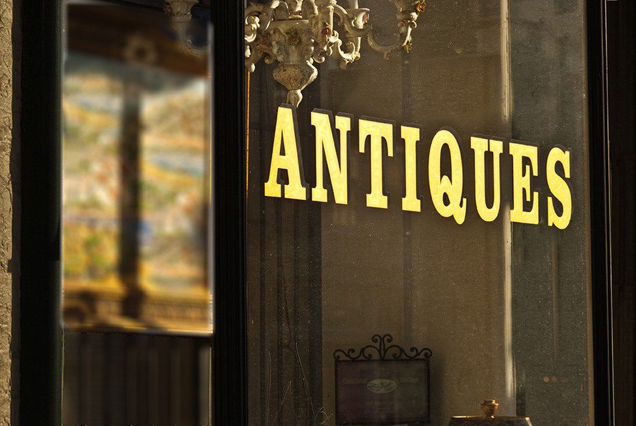 A sign that says antique on the front of a store.