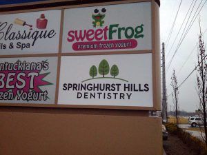 A sign for the dentist is posted on the side of the building.