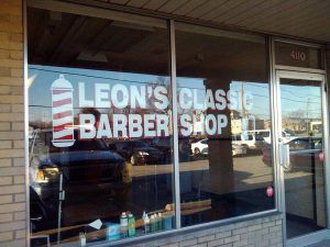 A barber shop window with the name of leon 's classic barbershop.