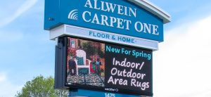 A large sign for carpet one in front of the building.