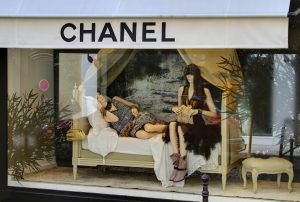 A store window with two women sitting on a bed.