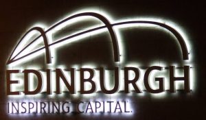 A lighted sign that says edinburgh, featuring capital.