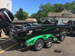 A green and black boat is parked in the street.